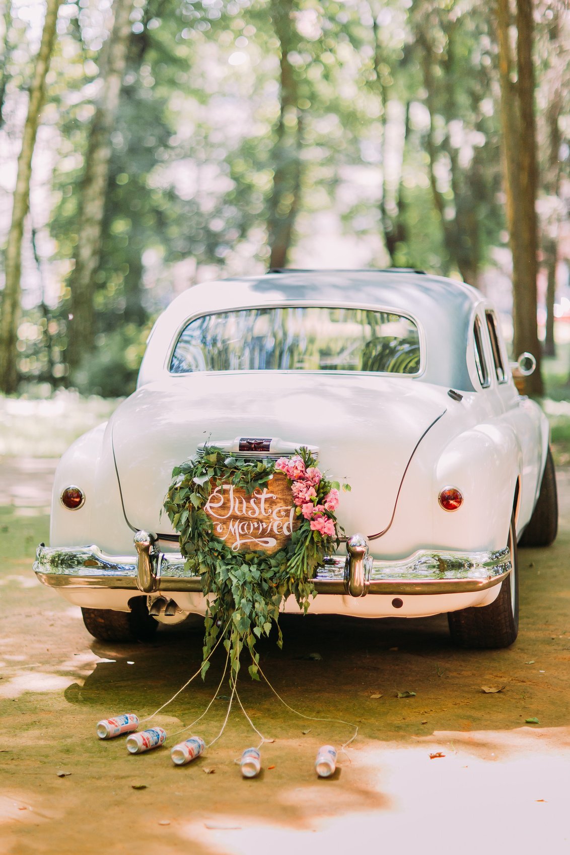 Bumper of retro car with just married sign and cans